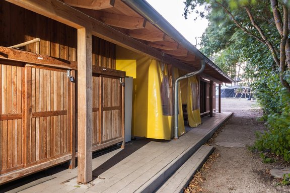 Blick auf Gebäuderückseite, links Holzschänke, Zwischengang ist mit gelben Planen abgehängt